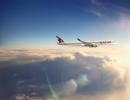 Blick aus dem Flugzeugfenster auf einen anderen Flugzeugflügel und den Himmel mit Wolken darunter