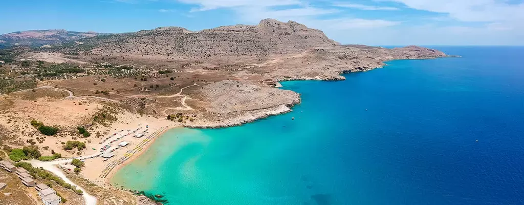 Küstenlandschaft von Rhodos mit klarem türkisfarbenem Wasser, felsigen Hügeln und einem kleinen Strandabschnitt